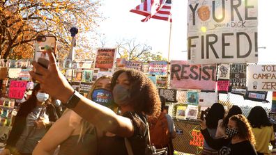 Supporters of US President-elect Joe Biden and his running mate Vice President-elect Kamala Harris pose for selfies near the security fence on the north side of the White House