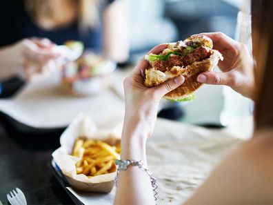 A woman eating a burger in a restaurant.