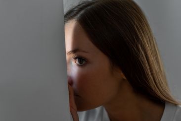 Woman scared looking through the window seeking safety neighbour