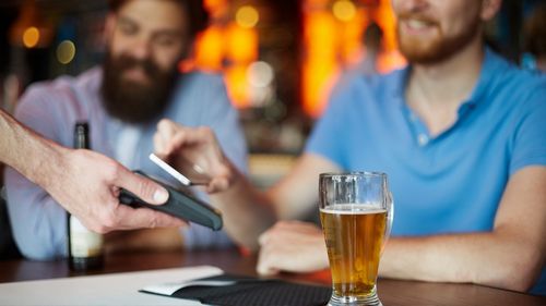 Paying for drinks at bar eftpos beer men at nightclub pub alcohol