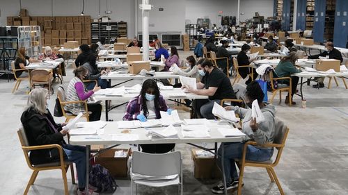 Officials work on ballots at the Gwinnett County Voter Registration and Elections Headquarters, Friday, Nov. 6, 2020, in Lawrenceville, near Atlanta