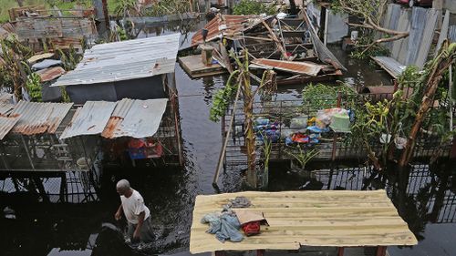 Farmer Victor Lozada searches for items that can be salvaged from his shed in Loiza. (AAP)