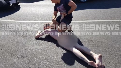 "Where's your clothes brother?," one of the bystanders asked during the arrest. (9NEWS)