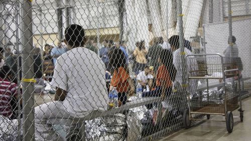 In this photo provided by US Customs and Border Protection, people who've been taken into custody related to cases of illegal entry into the United States, sit in one of the cages at a facility in McAllen, Texas, Sunday, June 17, 2018.