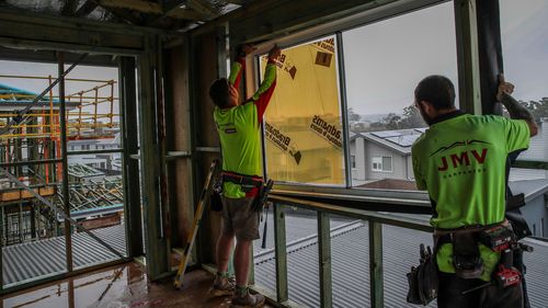 Workers install a window at a construction site