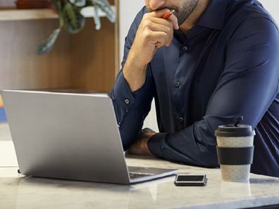 Serious mid adult professional looking at laptop.