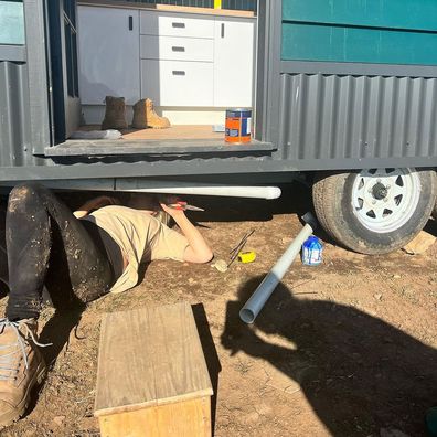 Aimee Stanton working under one of her tiny houses.