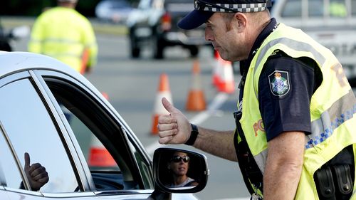 A motorist  is given the thumbs up by a police officer after being stopped at a checkpoint on the Gold Coast Highway at Coolangatta on the Queensland/NSW border,