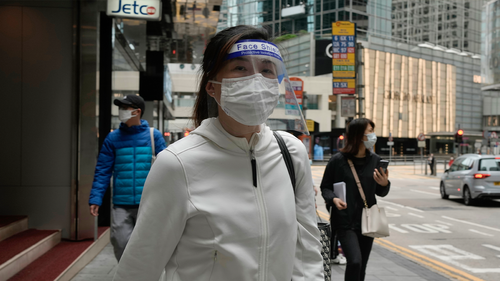 A woman wearing protective mask walks at a street in Hong Kong, Tuesday, March, 29, 2022. (AP Photo/Vincent Yu)