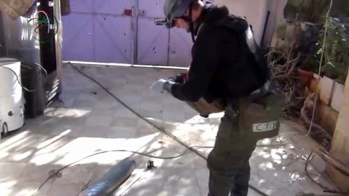 A presumed UN staff member photographs a canister in Damascus in August 2013. (File via AP)