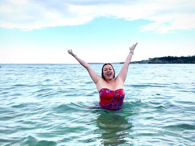 Shelly Horton in the ocean posing with her arms up in glee