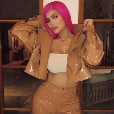 A pink-haired Kylie rocks a brown latex pantsuit.
