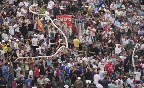 Fans in the stands make a beer snake out of empty plastic pint cups during the second day of the 2nd test cricket match between England and South Africa at the Old Trafford, in Manchester, England, Friday, Aug. 26, 2022.