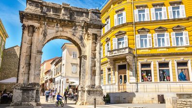 Ancient Roman triumphal arch or Golden Gate and sunny square in Pula, Croatia, Europe