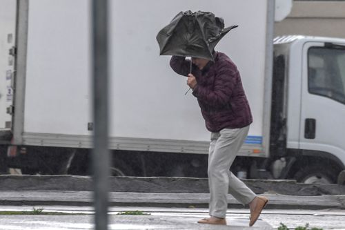 Commuters are battling against their umbrellas as wind combines with downpours of rain. Picture:AAP