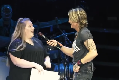 Keith Urban with fan on stage.