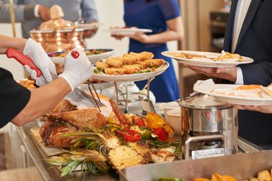 Cropped imaged of waiter cutting turkey for guests