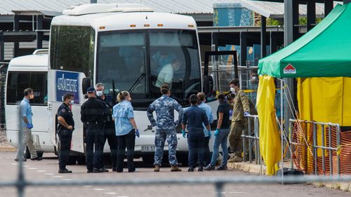 Multiple government agencies gather beside buses to take Australian evacuees from the coronavirus-struck cruise ship Diamond Princess after they arrived on a Qantas flight from Japan at Darwin International Airport in Darwin, Thursday, February 20, 2020.