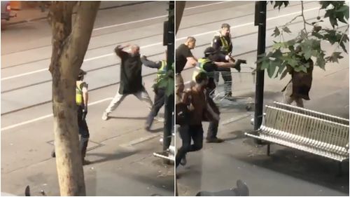 A man is shown attacking police officers on Bourke Street this afternoon.