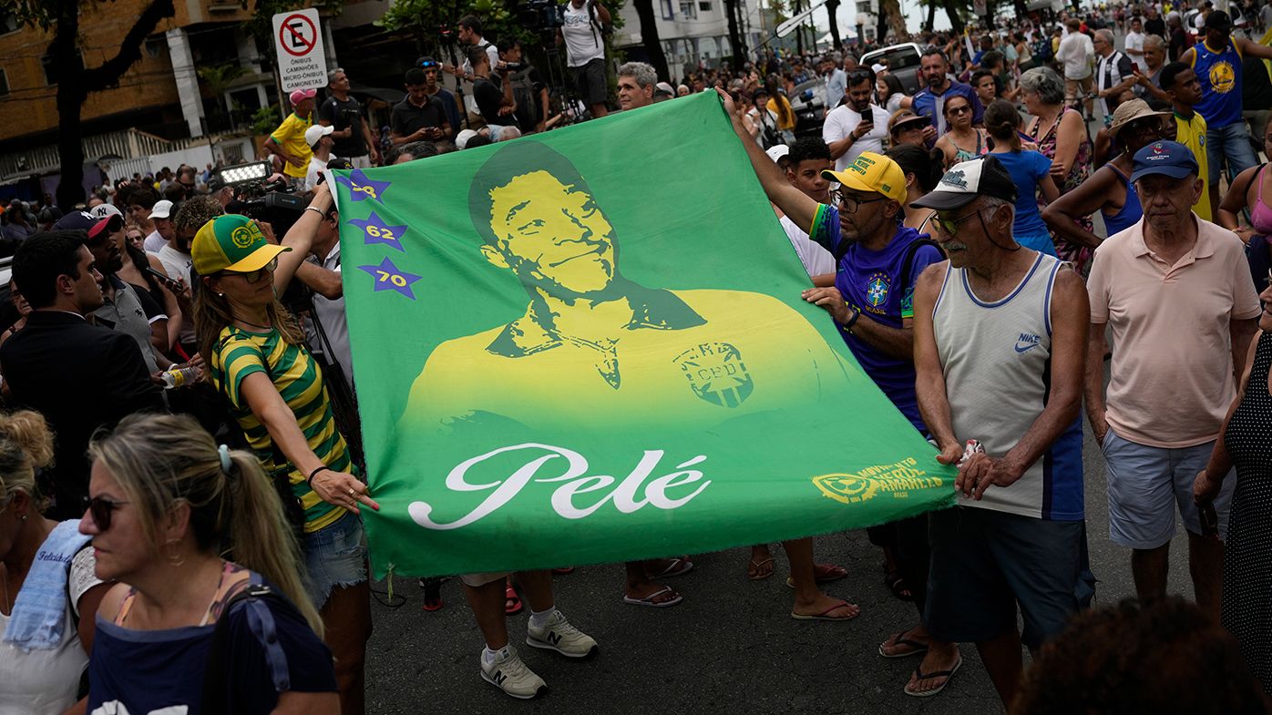 Fans hold a banner of the late Brazilian football great Pele along the route of his funeral procession from Vila Belmiro stadium to the cemetery in Santos, Brazil.