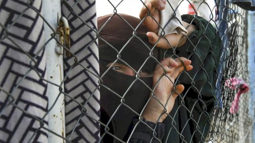 A woman at the fence line of the foreign section of al-Hawl camp.