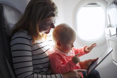 Mom and child playing tablet while flying on plane