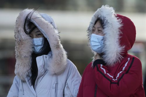 Women wearing masks to curb the spread of the coronavirus walks against strong wind in Beijing, China, Thursday, Dec. 30, 2021. (AP Photo/Ng Han Guan)