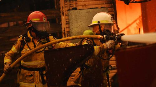 Rural Fire Service firefighters extinguish a fire on a property on January 23, 2020 in Moruya.