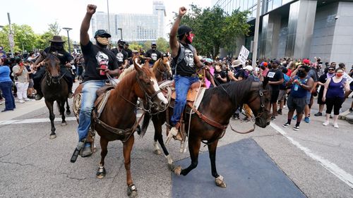 People march and ride horses to protest the death of George Floyd in Houston. Floyd died after a Minneapolis police officer pressed his knee into Floyd's neck for several minutes even after he stopped moving and pleading for air.