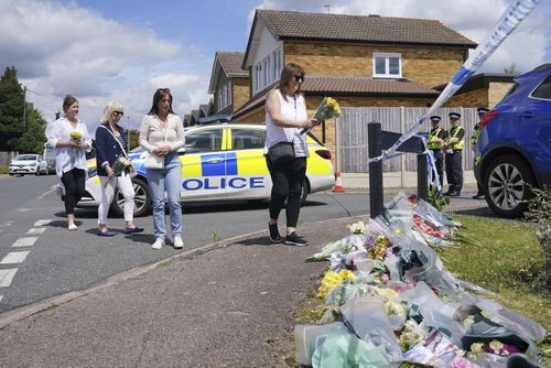 Family friend Lea Holloway, left, arrives with others to place tributes following the deaths of three women who were killed in an attack at their home, on Tuesday in Bushey, England, Thursday July 11, 2024.  