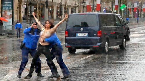 The protester, with the words 'fake peacemaker' written on her chest, is tackled by police.