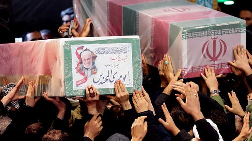 Iranian mourners carrying caskets of slain Iranian military commander Qasem Soleimani (L) and Iraqi paramilitary chief Abu Mahdi al-Muhandis at Tehran University in the Iranian capital