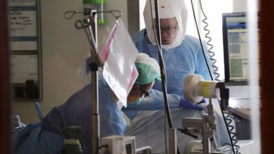 Registered nurses Beth Andrews, top, and Erin Beauchemin work with a patient in the COVID-19 Intensive Care Unit at Harborview Medical Center in Seattle.