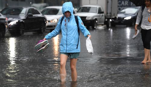 Pedestrians walk through flood waters at the corner of Clarendon and Cecil Street in South Melbourne, 