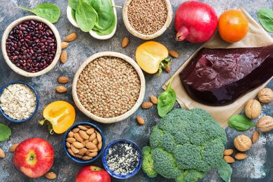 Foods high in iron. liver, broccoli, persimmon, apples, nuts, legumes spinach pomegranate Top view flat lay