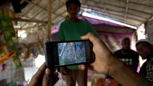 ohingya Muslim refugee Mohammad Karim, 26, shows a mobile video of Gu Dar Pyin's massacre inside his kiosk in Kutupalong refugee camp, Bangladesh. (AAP)