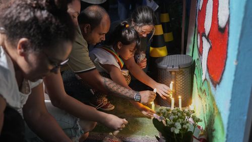 eople place lit candles outside the "Cantinho do Bom Pastor" daycare center after a fatal attack on children in Blumenau, Brazil.