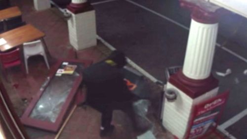 A hooded figure gets to work on stealing the ATM