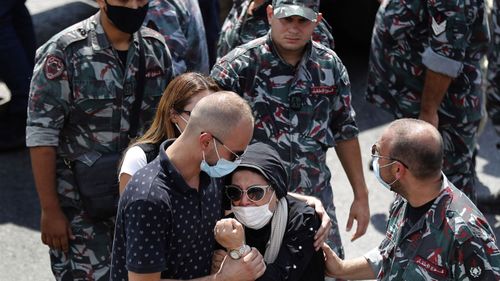 Relatives of Rami Kaaki, one of ten firefighters who were killed during the last week's explosion that hit the seaport of Beirut, mourn during his funeral, at the firefighter headquarters in Beirut, Lebanon, Tuesday, Aug. 11, 2020