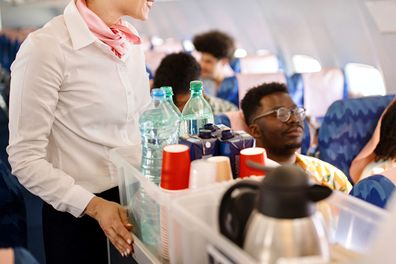 Cabin crew pushes the service cart and serves the customer on the plane during the flight