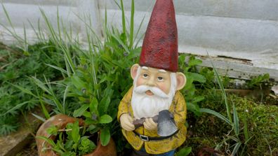 Garden gnome with yellow short and red cone hat holding an axe