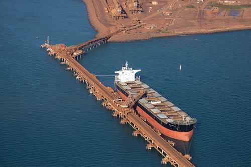 An iron ore stacker loads one of the holds of the cargo ship 'Bulk Integrity' at one of Rio Tinto's four dedicated port sites on the Burrup Peninsula in the Pilbara Region of Western Australia.