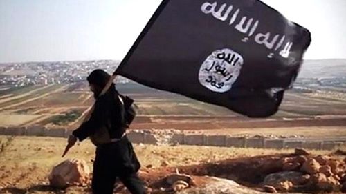 A man carries the Islamic State flag through a field, near an unknown town in the now fallen, self-declared caliphate.