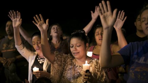 Mourners participate during a candlelight vigil held for the victims of a fatal shooting. (Image: AAP)