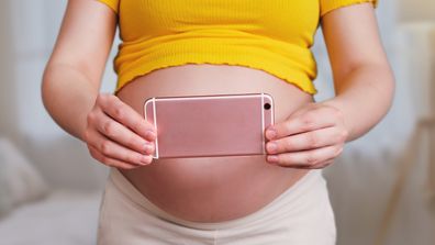 Shooting videos and photos on the phone in the hands of a pregnant woman