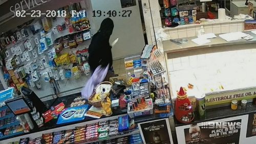 The robber jumps the counter and follows, demanding money.
