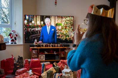 On his first Christmas Day broadcast to the nation since the death of his mother, Queen Elizabeth III in September, King Charles III speaks to a suburban family on their widescreen TV in their living room that is filled with wrapped presents, on 25th December 2022, in Nailsea, England 
