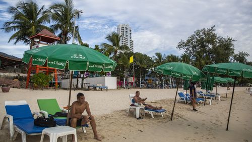  Tourists lay in lounge chairs on Patong Beach, Thailand's most popular beach.