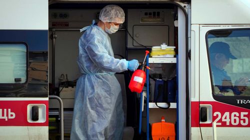 A medical worker wearing protective equipment sprays disinfectant at his ambulance after delivering a patient suspected of being infected with the coronavirus to the Pokrovskaya hospital in St.Petersburg, Russia, Monday, May 4, 2020. (AP Photo/Dmitri Lovetsky)