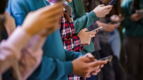 Gruppo di adolescenti che utilizzano i telefoni cellulari nel corridoio della scuola